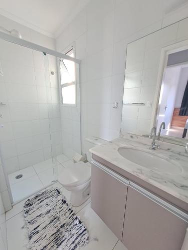 a white bathroom with a toilet and a sink at Apto no Itaguá - Varanda Gourmet e Lazer completo in Ubatuba