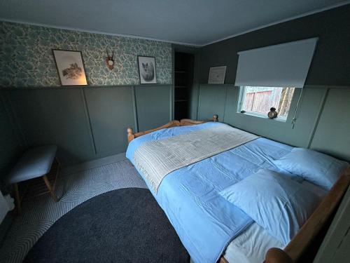 a bedroom with a bed with blue sheets and a window at Farmstay Hunters Cabin, 2p in Årjäng