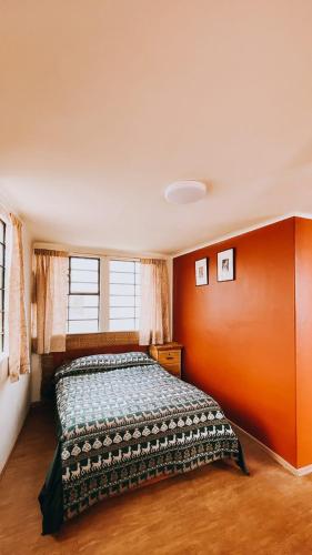 a bedroom with a bed with an orange wall at Royal Frankenstein Hostel in Cusco