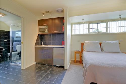 a bedroom with a bed and a small kitchen at Aloft Boutique Accommodation in Strahan