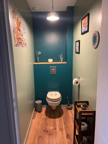 a bathroom with a toilet and a blue wall at Le Clos Louisiane in Saint-Loup-Hors