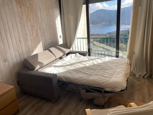 un lit dans une chambre avec une grande fenêtre dans l'établissement Studio Cabine avec WIFI et vue splendide sur le lac et les montagnes, aux Angles