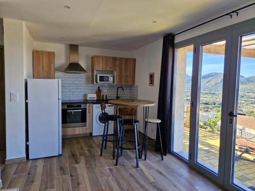 une cuisine avec un réfrigérateur et une table avec des tabourets dans l'établissement Vos vacances à 3 minutes de la mer, à Belgodère