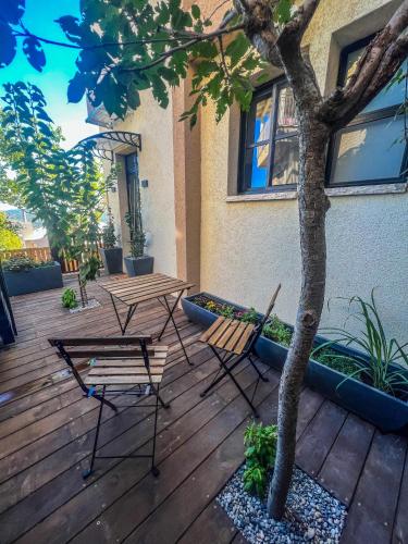 two tables and chairs on a wooden deck with a tree at Lana's Guest House in Ḥurfeish