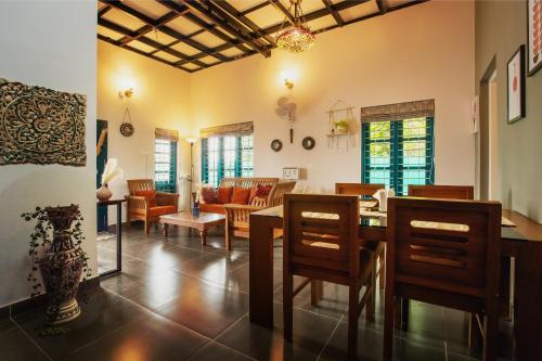 a dining room and living room with a table and chairs at Lakefront 2BHK villa I Cozy A-frame balcony deck & BBQ grill in Kollam