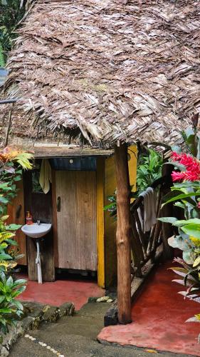 a small house with a sink and a straw roof at El Hotelito Perdido in Rio Dulce