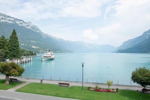a boat in a lake with mountains in the background at Seiler au Lac in Bönigen