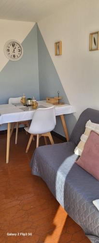 - une chambre avec 2 lits, une table et une horloge dans l'établissement Appartement-1- prive, terrasse, parking et jardin, au Boulou