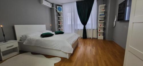 a bedroom with a bed with white sheets and green pillows at Apartament Victoriei - Centru in Bucharest