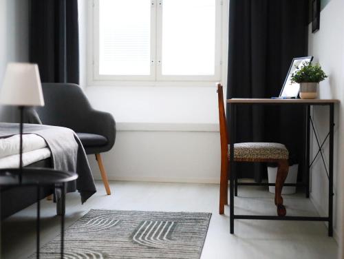 a bedroom with a window and a chair and a table at Hostel Bjorkenheim in Seinäjoki