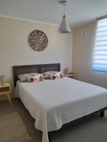 a bedroom with a large white bed with two pillows at Familiar departamento en Villarrica in Villarrica