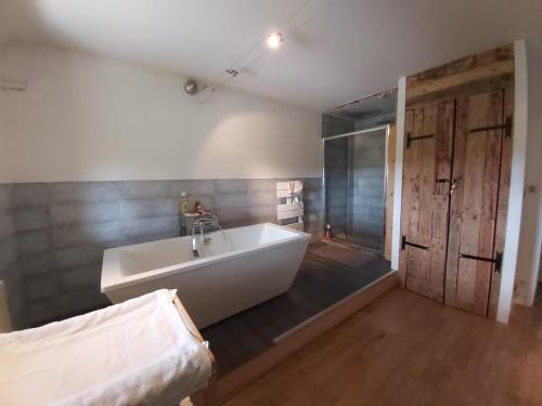 La salle de bains est pourvue d'une grande baignoire blanche et d'une douche. dans l'établissement Beautiful renovated farmhouse of 250m with 3400m of garden, à Saint-Savin