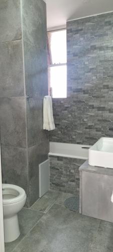 a bathroom with a toilet and a tub and a sink at Oceanic Unit 67 - North Beach in Durban