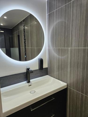 une salle de bain avec un lavabo et un miroir dans l'établissement Le Cocon de Marine, à Triel-sur-Seine