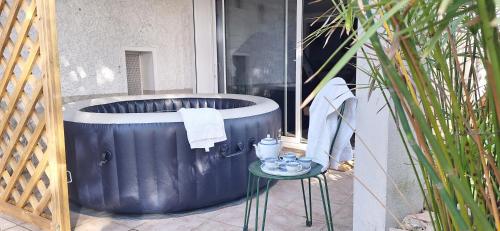 a blue tub sitting outside of a window with a table at Lé Luquentia, demeure de charme, piscine, grand jardin, spa, billard in Gujan-Mestras