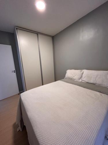 a bedroom with a white bed and two closets at Apartamento Cop 30 in Ananindeua