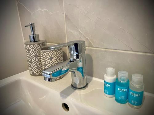 a sink with a faucet and two bottles on it at Florence Coach-House-Parking-WIFI King bedroom & double bedroom in Peterborough