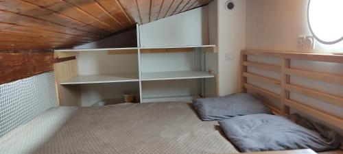 a small room with a bed and shelves at Petit Appartement dans les Arbres in Carcans