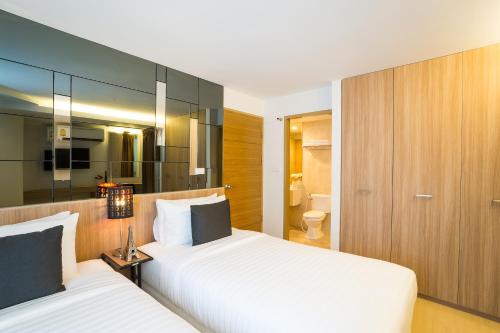 a hotel room with two beds and a bathroom at Beyond Suite in Bangkok