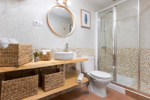 Un baño con inodoro, lavabo y espejo. en 2BR El Cotillo House - Private Terrace, en Cotillo