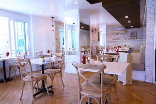 a restaurant with white tables and chairs and a counter at At Residence Suvarnabhumi Hotel - SHA Extra Plus in Lat Krabang