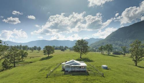 ein Haus auf einem Feld mit Bergen im Hintergrund in der Unterkunft Black Cockatoo Tyalgum in Tyalgum
