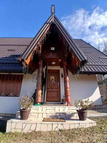 a small white house with a wooden door at Forest house ALEKSANDAR in Srbac