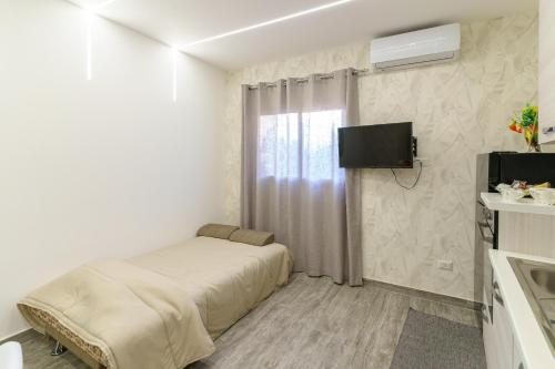 a white room with a bed and a tv on the wall at Belsito Suite in Misterbianco