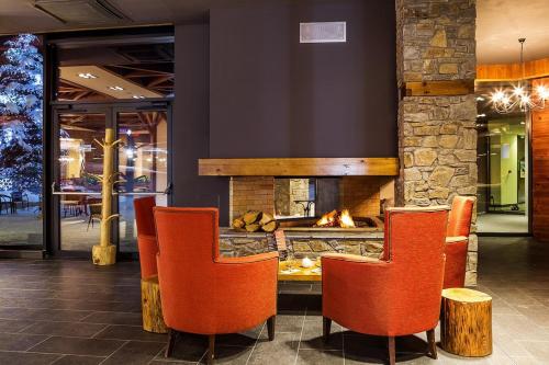 a lobby with a fireplace and orange chairs at Rila Hotel Borovets in Borovets