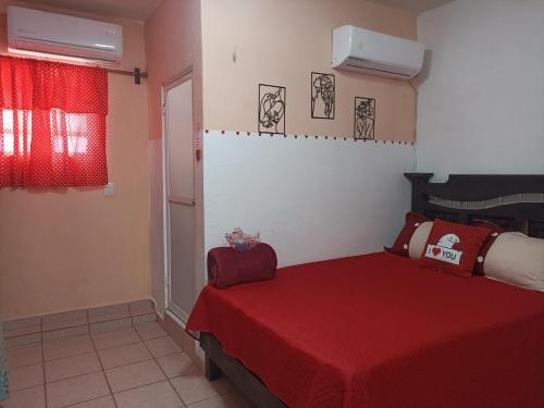a bedroom with a red bed with a red blanket at Casa Chero in Comalcalco