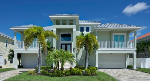 a large house with palm trees in front of it at Memories on Madison by Sun Palace Vacations in Fort Myers Beach