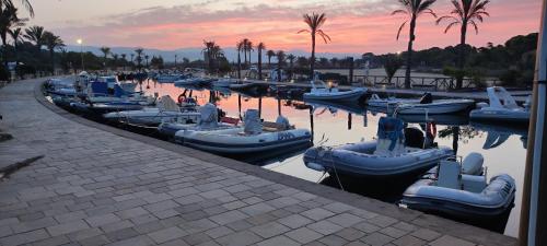 un gruppo di imbarcazioni ormeggiate in acqua al tramonto di Casa del Pino a Porto Pino