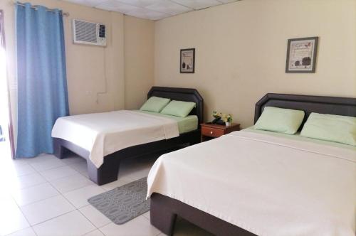 a bedroom with two beds and a blue curtain at Residencial Tropical in La Chorrera