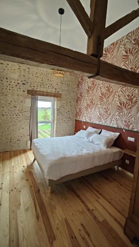 une chambre avec un grand lit avec un plancher en bois dans l'établissement Les Écrins de Mounet, à Bats