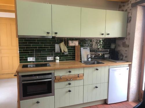 une cuisine avec des armoires blanches et un réfrigérateur blanc dans l'établissement La Ruisselle, à Chissey-en-Morvan