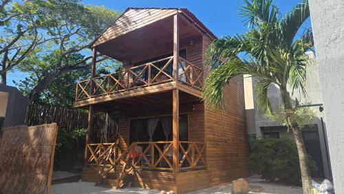 a wooden building with a balcony and a palm tree at Blue Caribe Bacalar Front Lagoon in Bacalar