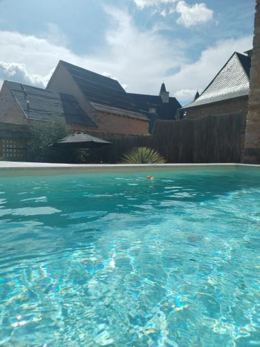 une piscine d'eau bleue devant une maison dans l'établissement Auberge du donjon Chambre chocolat, à Bournazel