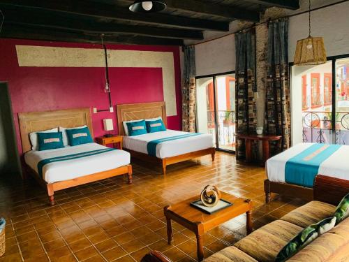 a hotel room with two beds and a couch at Posada La Plazuela in Cuetzalán del Progreso