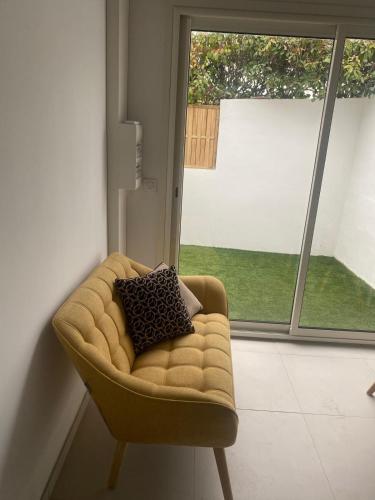 a couch with two pillows on it in front of a window at nouvelle appartement T2 mezzanine et piscine in Valergues