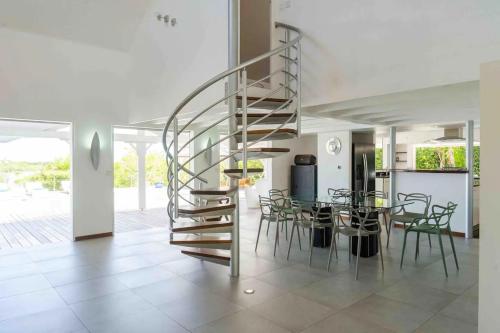 a spiral staircase in a living room with a table and chairs at All-Inclusive Experience at Villa Azur in Les Terres Basses
