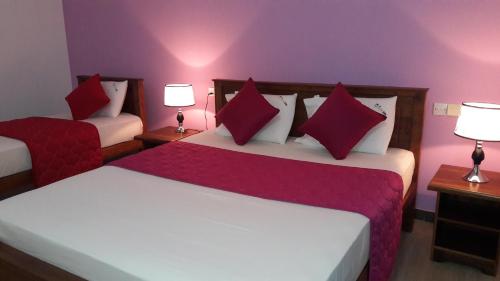 a bedroom with two beds with red pillows at New Rani Inn in Negombo