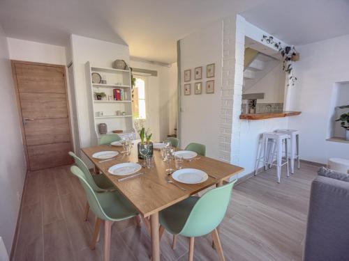 une salle à manger avec une table en bois et des chaises vertes dans l'établissement New Lovely cosy house with garden, à Faremoutiers