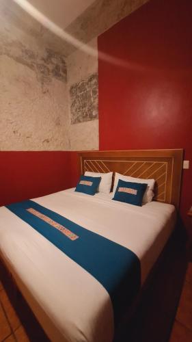 a bed with blue and white pillows in a room at Posada La Plazuela in Cuetzalán del Progreso