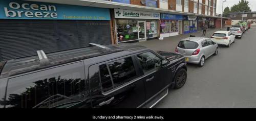 a black limo parked on a city street with cars at Newly built modern flat with free parking close to London Luton airport and L&D hospital in Dunstable