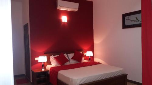 a red bedroom with a bed and two lamps at New Rani Inn in Negombo