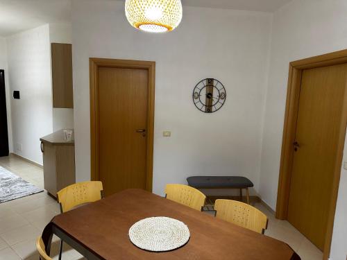 a dining room with a table and chairs and a clock at Maren apartment in Orikum
