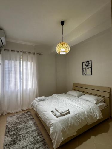 a bedroom with a large white bed with a chandelier at Maren apartment in Orikum