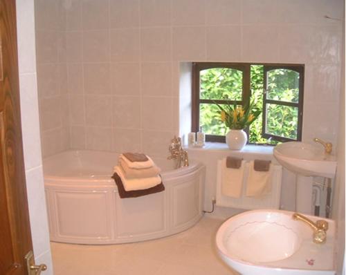 蘭戈倫的住宿－馬蹄之徑假日酒店，白色的浴室设有浴缸和水槽。