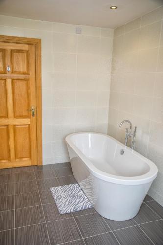 a large white tub in a bathroom with a door at Beechwood Country House in Killarney