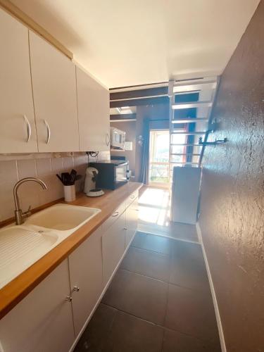 une cuisine avec des armoires blanches et un évier dans l'établissement T2 mezzanine avec loggia vue montagne au Port de Saint-Cyprien, à Saint Cyprien Plage